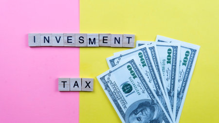 Investment Tax Concept. Selective focus on a fake money and a wood tiles on a yellow and pin backgroundの写真素材