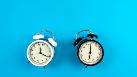 Selective focus on a black and white alarm clock on a blue background. A copy space of a clock concept. Time Conceptの写真素材