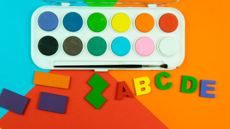 A palette of water color, alphabet and shapes on a colored background. Selective focus on the alphabet.の写真素材