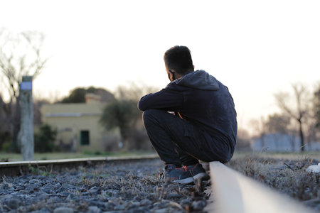 Lonely teenager sitting on the railroad tracks. Freedom and loneliness concept.の写真素材