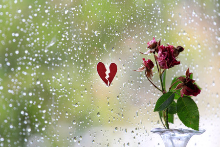 Raindrops on the window, broken heart painted on the glass.の写真素材