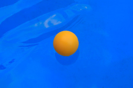 Yellow ball floating in blue swimming pool. Top view. Copy space.の写真素材