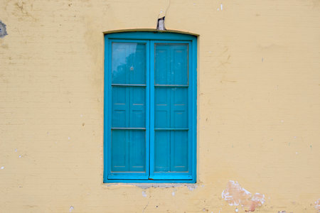 Vintage blue window on yellow wall, closeup of photo.