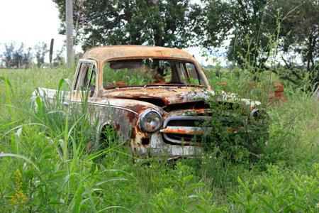 Abandoned old rusty car in a meadow of grass.の写真素材