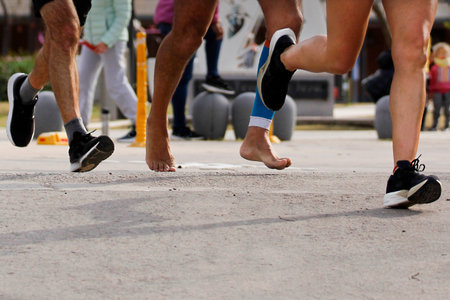 Marathoner running barefoot, closeup of his feet