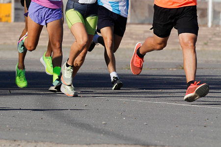 Marathon running race, people feet on city road, detail of sport trainingの写真素材