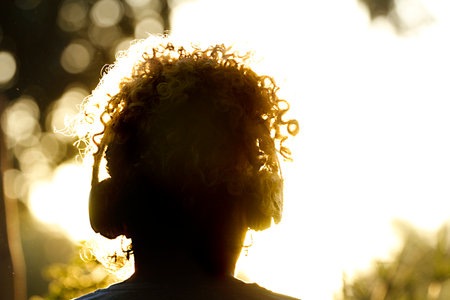 Silhouette of a woman with curly hair listening to music with headphonesの写真素材
