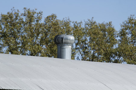 Metal chimney on the roof of a building against the blue sky