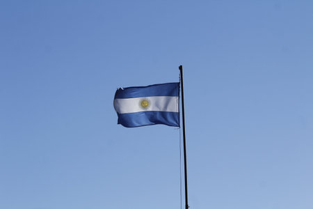 National flag of Argentina on a flagpole against the blue sky.