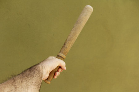 A baseball bat in a man's hand on a green background.の写真素材