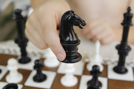 Close up of hand of businesswoman playing chess with black horse on chessboard