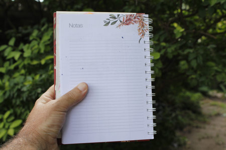 Notebook in a man's hand on the background of nature.