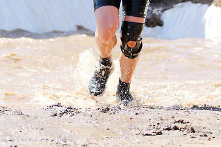Marathon running on sand, closeup of legs and water splashes