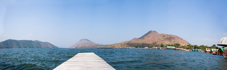 Mountain lake and flowing river with a wooden bridge の写真素材