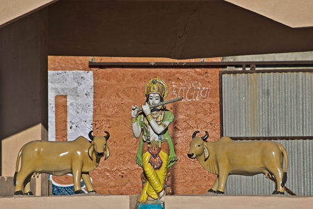 FEB 09, 2015,  DWARKA, INDIA - Sculpture of Shri Krishna playing flute andtwo cows over the gate of goshala (farm)のeditorial素材