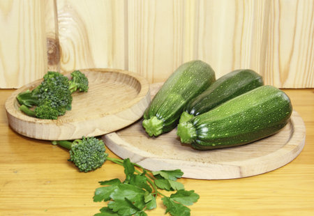 Cabbage of a broccoli and vegetable marrows on a wooden plateの写真素材