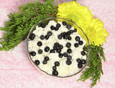 A glass vase with cottage cheese and bilberry berries on a pink background の写真素材
