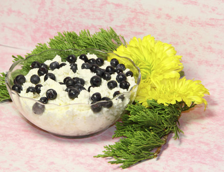 A glass vase with cottage cheese and bilberry berries on a pink background の写真素材