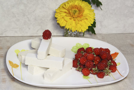 The sweet white fruit candy and a raspberry on a dish の写真素材