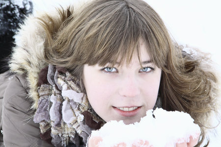 The beautiful girl lays with snow in handsの写真素材