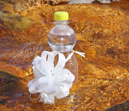 A bottle mineral waters on stones in water with a bow の写真素材