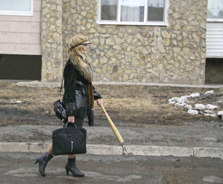 The woman goes along the street with a bat and the laptop の写真素材