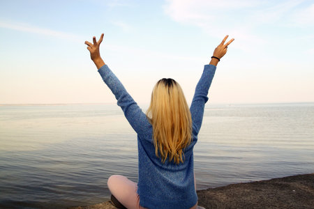 Young girl with arms raised above the head on the shore of the sea, freedom conceptの写真素材
