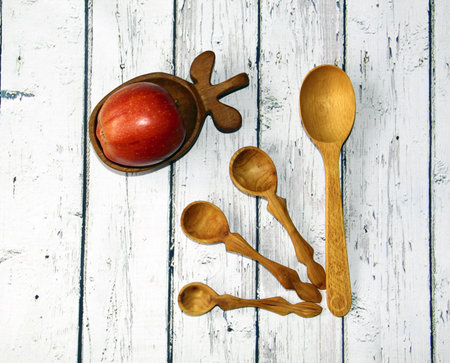 Wooden kitchen spoon and plate with an apple on the table, top viewの写真素材