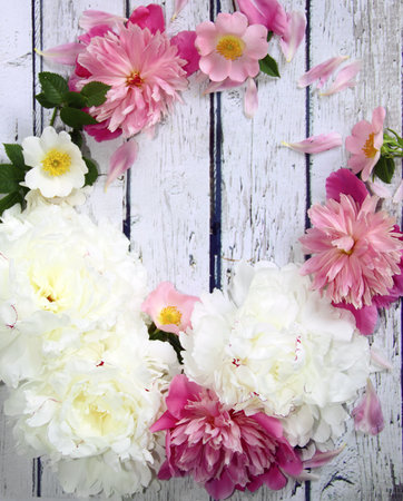 A beautiful wreath of peony and dog rose flowers on a wooden background, rustic styleの写真素材
