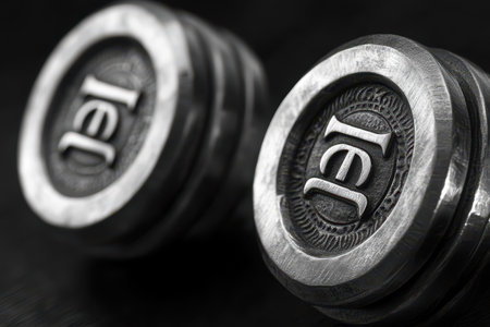 Close-up view of gym weights featuring a metallic finish and brand logo. Perfect for strength training, these weights are essential for building muscle and enhancing fitness routines.の素材