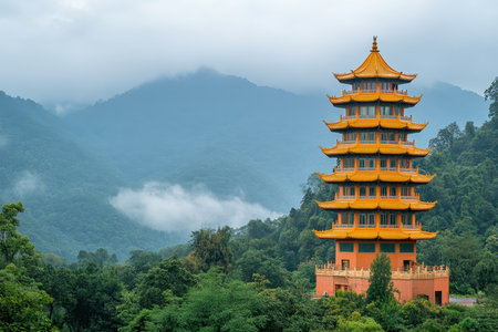 A striking pagoda with ornate golden roofs rises above dense trees, set against a backdrop of misty mountains and soft clouds, creating a tranquil atmosphere.の素材