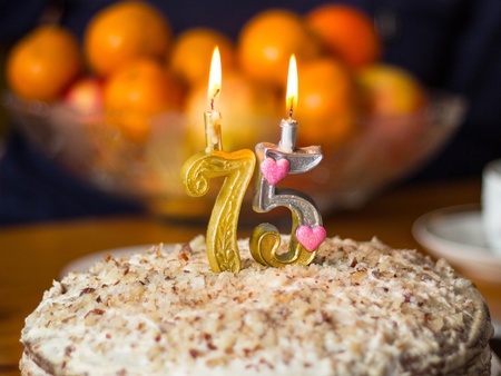 two candles on the birthday cake on the background of the vase with orangesの写真素材