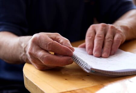 hand of an elderly man holding a notebook