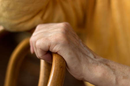 the hand of an elderly woman in a yellow jacket woman lying on a chairの写真素材