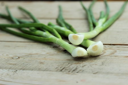 Three young peeled onions on a wooden tableの写真素材