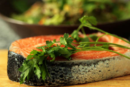 piece of red fish with a sprig of parsley on a cutting boardの写真素材