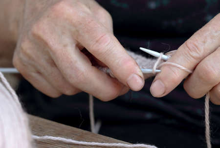 Hands of an elderly woman with knitting needles