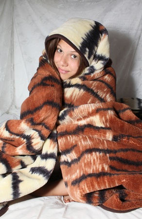 Young smiling girl wrapped in a blanketの写真素材
