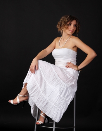 pretty young girl in a white dress sitting on a chairの写真素材