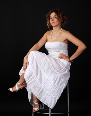 young girl in white dress sitting on a chairの写真素材