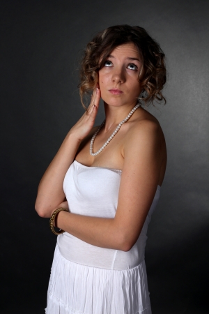 Young pensive dreamy blonde girl in a white dressの写真素材