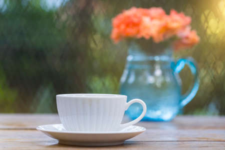A beautiful set of white coffee mugs on a wooden table in a natural setting in the morning.の写真素材