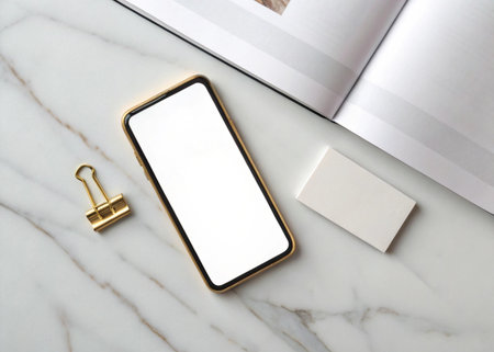 Smartphone with blank screen and stationery on white marble background.の写真素材