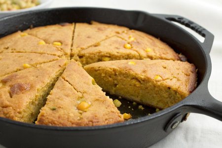 Homemade cornbread in a cast-iron skillet on a white background