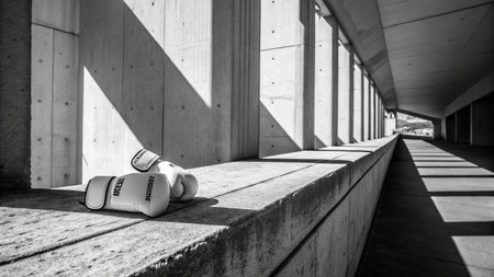 Black and white image of a pair of boxing gloves lying on a concrete benchの写真素材