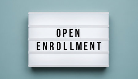 a bright sign reads open enrollment in bold black letters on a crisp white board with a light blue background.の写真素材