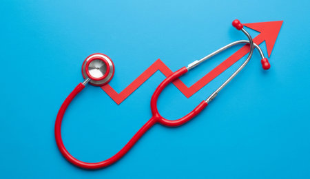 a red stethoscope lies on a blue background with a red arrow pointing upwards, symbolizing rising healthcare costsの写真素材