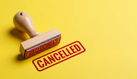 a wooden cancelled stamp sits on a yellow backdrop, showing a clear message of termination or invalidation.の写真素材