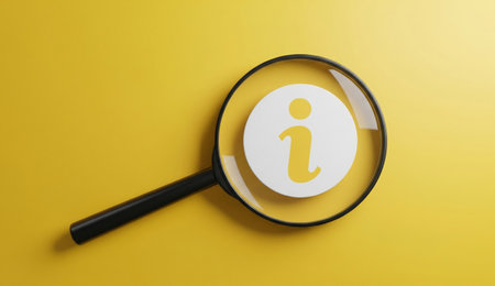 a magnifying glass is focused on a white circle with a yellow information icon against a bright yellow backgroundの写真素材