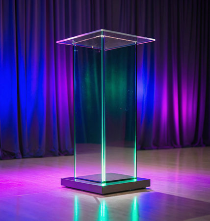 Empty glass trophy stand in front of the stage curtain with lighting effectの写真素材